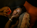 Mutter Mitte 30 nachts auf dem Sofa mit dem Smartphone, nachdenklicher Gesichtsausdruck.